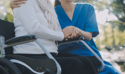A nurse take care a senior male on wheelchair in his garden at home