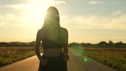 silhouette sports girl running along road sunset, sun setting, mountain trail running, enjoying...