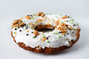 Christmas cake in sugar icing, with walnuts and almonds, on white glass, close-up