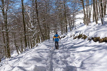 Hiker with snowshoes in backpack walked on snowy mountain