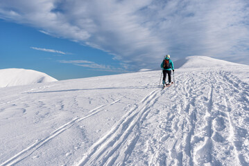Fototapeta na wymiar Skier woman climbs the snowy hill. ski touring