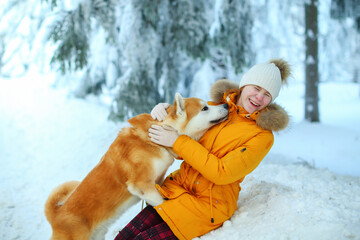 A girl with her Japanese Akita Inu dog for a walk in a field in winter.