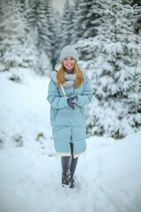 Portrait of a smiling woman in a snowy forest enjoying a winter day. Young traveler posing outdoors