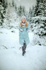 Fototapeta na wymiar Girl play with snow in a snowy forest enjoying a winter day. Young traveler posing outdoors