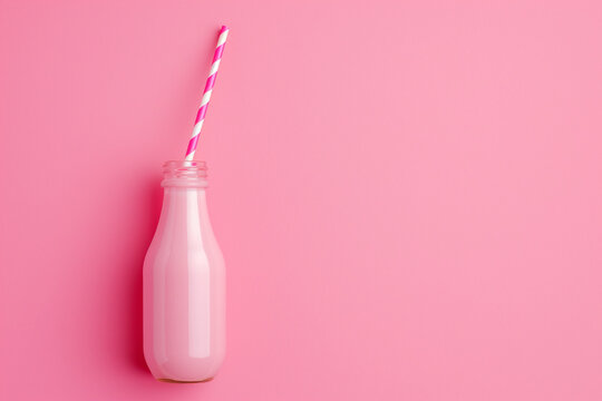 Monochromatic composition of pink bottle with pink stripes straw on pink background. Copy space. Minimal concept