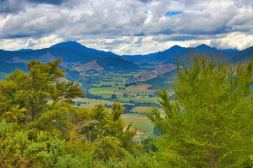 Fototapeta premium Green valley with high, forested hills under a cloudy sky, near Pelorus Bridge, Marlborough Sounds, South Island, New Zealand 