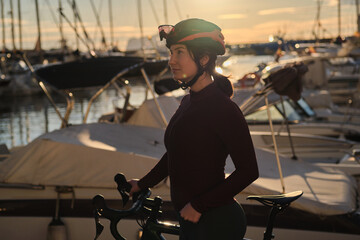 Portrait of beautiful female cyclist wearing cycling kit, glasses and helmet during sunset on yucht...