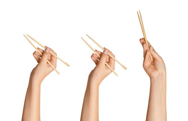 A set of female hands holding wooden chopsticks for sushi or rolls on a blank background.