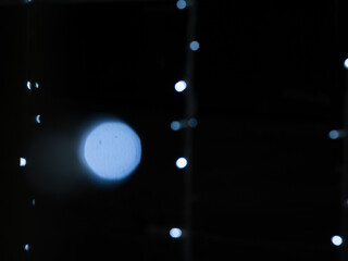 White lights of blinking garland in blur. Black blurred background for text or pictures