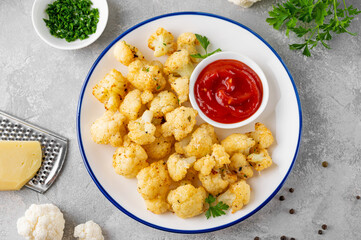 Baked cauliflower with parmesan cheese on a gray concrete background. Vegetarian healthy food.