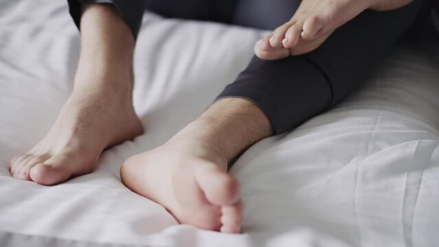Two people's feet interlocked in an intimate pose on white bedsheet, suggesting closeness comfor. focus is on bare feet and touch, implying relaxation, intimacy, or couple's moment of togetherness.
