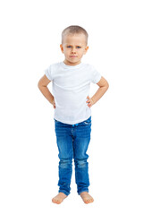 A serious frowning little boy stands with his hands on his belt. A child in a white T-shirt and blue jeans. Full height. Isolated on a white background. Vertical.