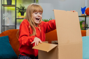 Happy shocked young child girl unpacking delivery parcel. Smiling satisfied teenager kid shopper, online shop customer opening cardboard box receiving purchase gift by fast postal shipping at home