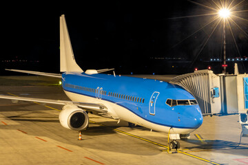 The plane is parked at the airport at night