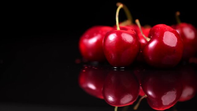 Cherries isolated on black background. Fresh ripe Cherry close-up. Rotating Organic red cherries isolated on black background. Heap of juicy organic Berries, border design