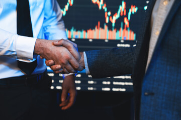 Investor stock trading of business partners shaking hands against screen for cooperating of...