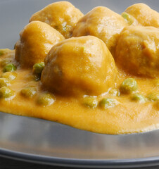 Close up, homemade plate of meatballs with tomato sauce and peas.