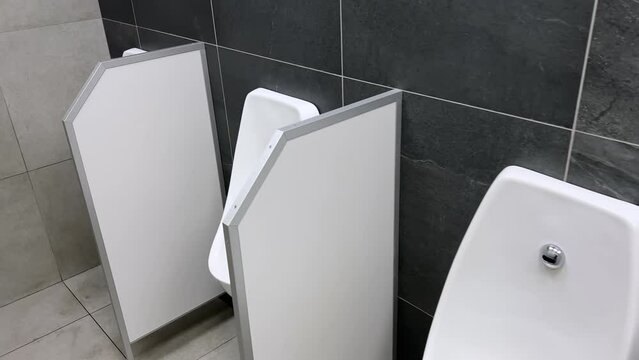Rows of modern urinals with a sensors WC flush in a public men's room