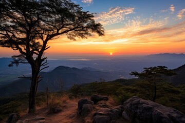 Fototapeta premium A stunning sunset view from a mountain trail, with the sun dipping below the horizon casting vibrant orange hues over the landscape
