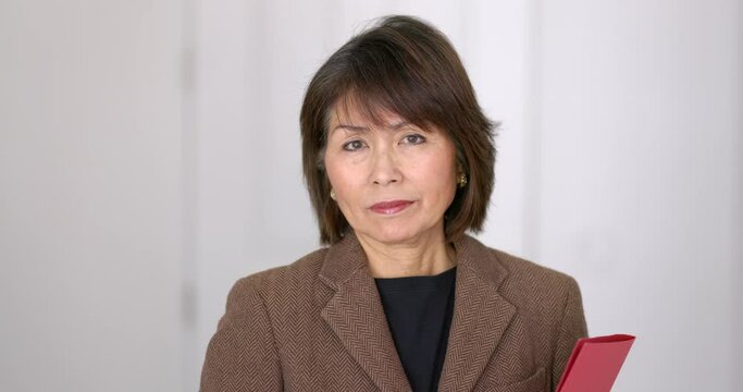 Portrait attractive stylish businesswoman closeup relaxing looking at camera holding red folder isolated. 