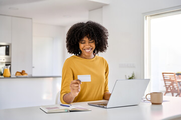Young adult smiling happy African American woman holding credit card using laptop computer paying...