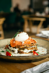 Vegetarian zucchini pancakes with poached egg, salmon and tomato, close up, healthy breakfast.