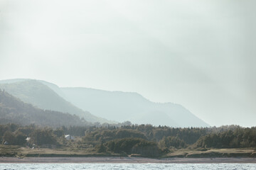 vue sur des collines au loin lors d'une journ&eacute;e brumeuse avec de l'eau en avant plan en &eacute;t&eacute;