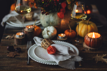 Atmospheric autumn elegant beautiful table setting with pumpkins for a wedding or thanksgiving family celebration. Fall decoration countryside rustic style, cozy home atmosphere , candles, wine