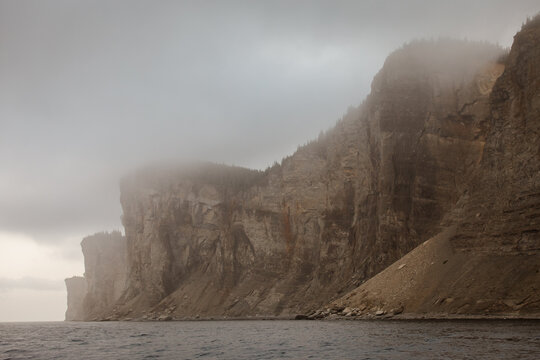 vue sur une paroi rocheuse avec le pic dans des nuages bas lors d'une journ&eacute;e d'&eacute;t&eacute; brumeuse