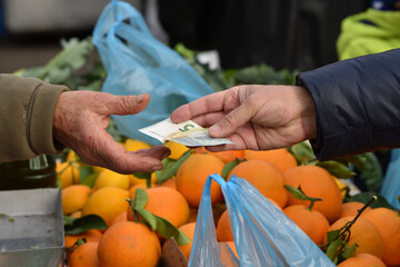 Zagreb, Croatia : 01,05,2024 : Elderly woman pays for vegetables at the vegetable market with euros.