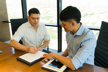 Businessman requesting his client's signature after reading an agreeing to a contract