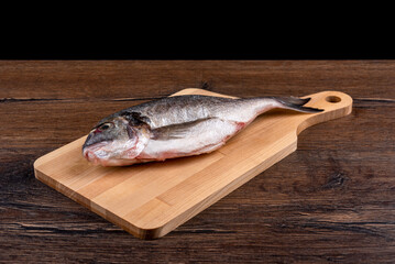 Raw dorado fish on a cutting board.