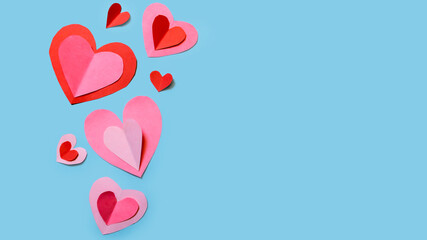 Banner with cute and delicate paper hearts arranged on a sky-blue background. Concept for Valentine's Day, Mother's Day, love, and friendship.