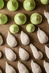 Meringue cakes in white and green colors, decorated with sugar beads, stand on the parchment paper
