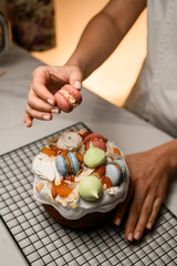 Confectioner decorates a birthday cake with macaroons, candied fruits
