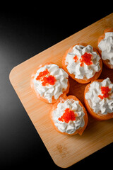 Sushi roll with salmon decorated with cream and caviar on a wooden board