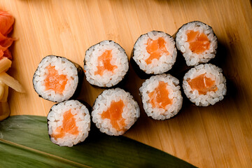Portion of sushi with salmon on a wooden board background