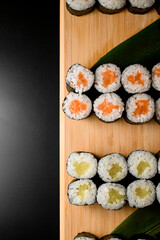 Set of sushi rolls of two types lie on a wooden board