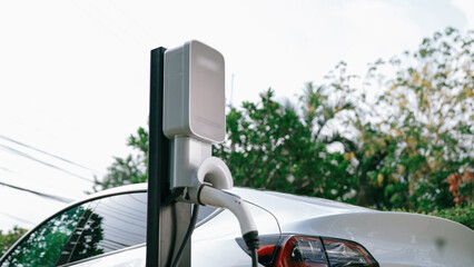 EV electric car recharge battery at parking lot in natural green city park. Alternative clean...