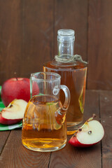Homemade Apple vinegar in a bottle and a jar with red and green apples on the table. Healthy dressing for a salad.