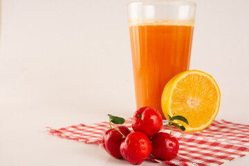 Fresh Organic Acerola and Orange Juice with sliced acerola and orange fruit in a glass cup in white background in top view