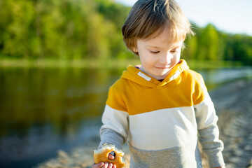 Adorable toddler boy having fun outdoors on sunny summer day. Child exploring nature. Summer activities for kids.