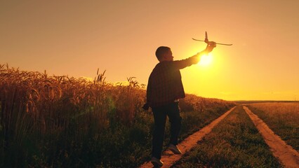 Boy child play with toy airplane, Teenager dreams of flying, becoming pilot Airplane. Child Boy dreams of flying into sky. Happy teen boy plays with toy plane on field. Authentic outdoor experiences