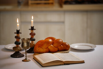 Challah bread covered, shabbat wine and Totah on the kitchen table. Traditional Jewish Shabbat ritual. Shabbat Shalom