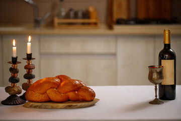 Challah bread, shabbat wine  on the kitchen table. Traditional Jewish Shabbat ritual. Shabbat...