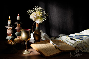 Shabbat wine, candles, Torah and Tallit on the kitchen table. Traditional Jewish Shabbat ritual....