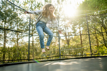 Teenage girl jumping on a trampoline in a backyard. Sports and exercises for children.