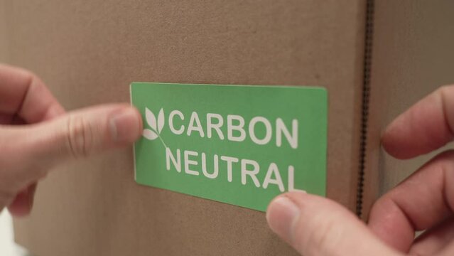 Green Carbon Neutral Label Being Put on a Box Closeup