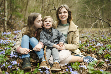 Two sisters and their toddler brother having fun during a hike in the woods on beautiful sunny...