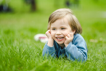 Cute toddler boy playing in blooming cherry tree garden on beautiful spring day. Adorable baby having fun outdoors.